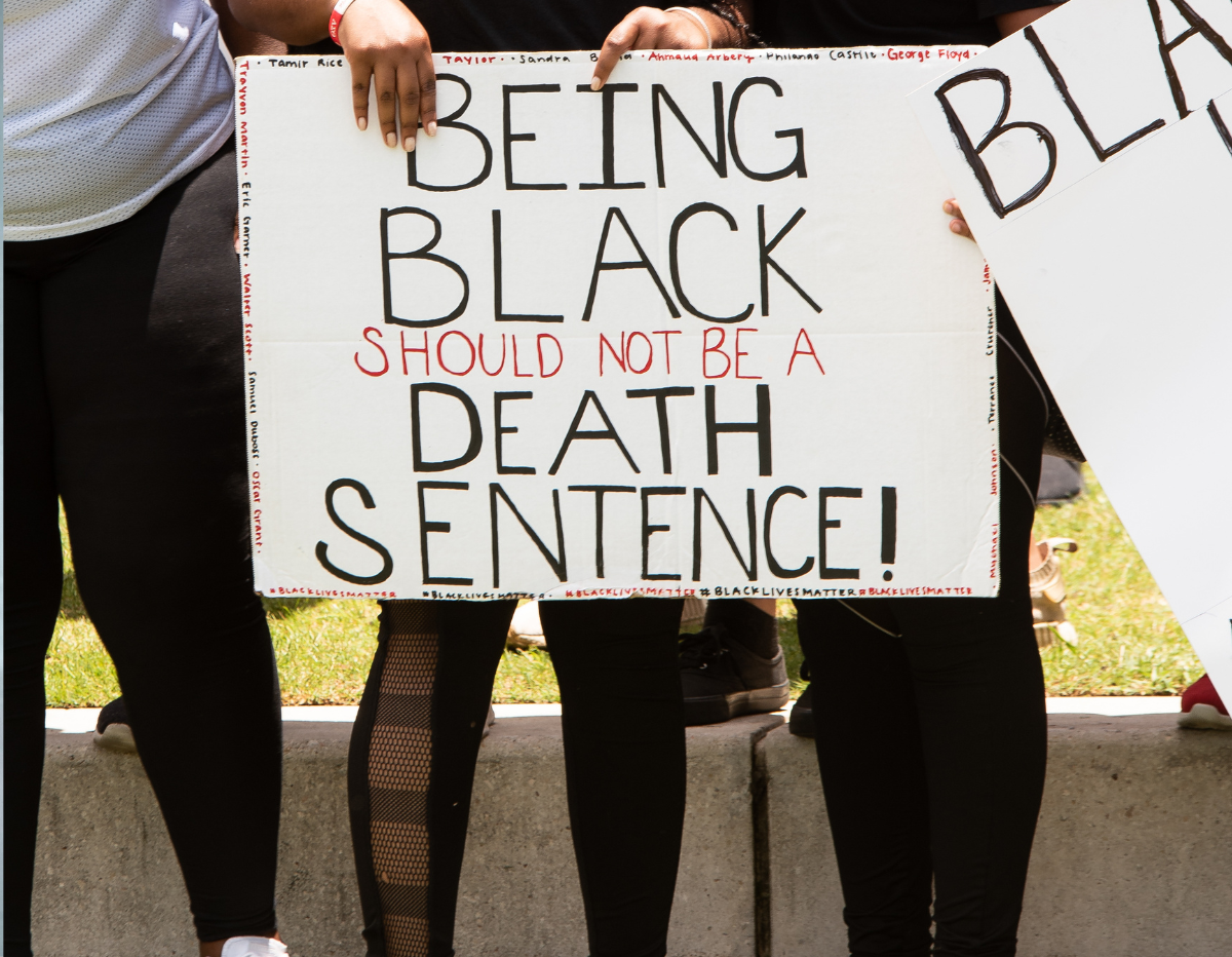 African American Woman Holding a "Being Black Should Not Be A Death Sentence" Sign